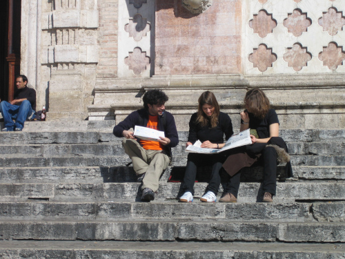 three people sitting on stairs comparing data collected during an OpenStreetMap field survey